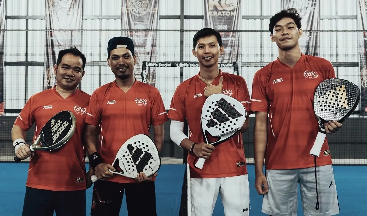 Empat pemain padel berjersey oranye NOIR memegang raket di dekat net.